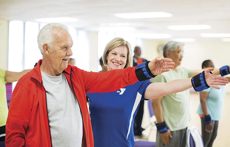 An active older adult receives advice from YMCA personal trainer